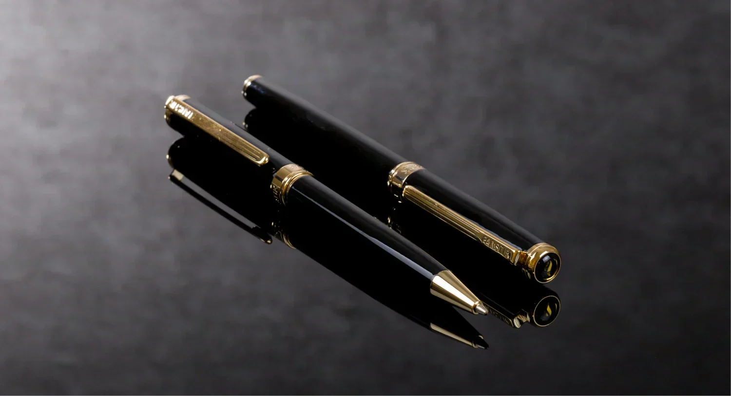 One Fanstik Luxury Rollerball Pen and One Fanstik Luxury Ballpoint Pen on a dark surface