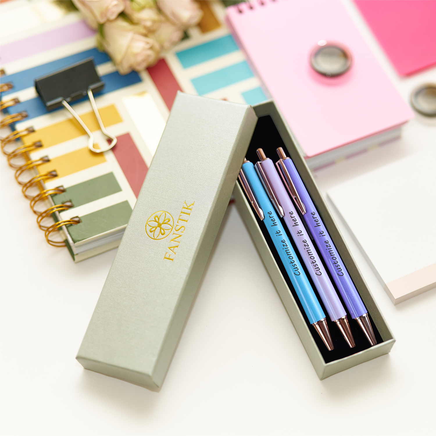 Fanstik three-color pen set displayed on a table with notebooks and notepads